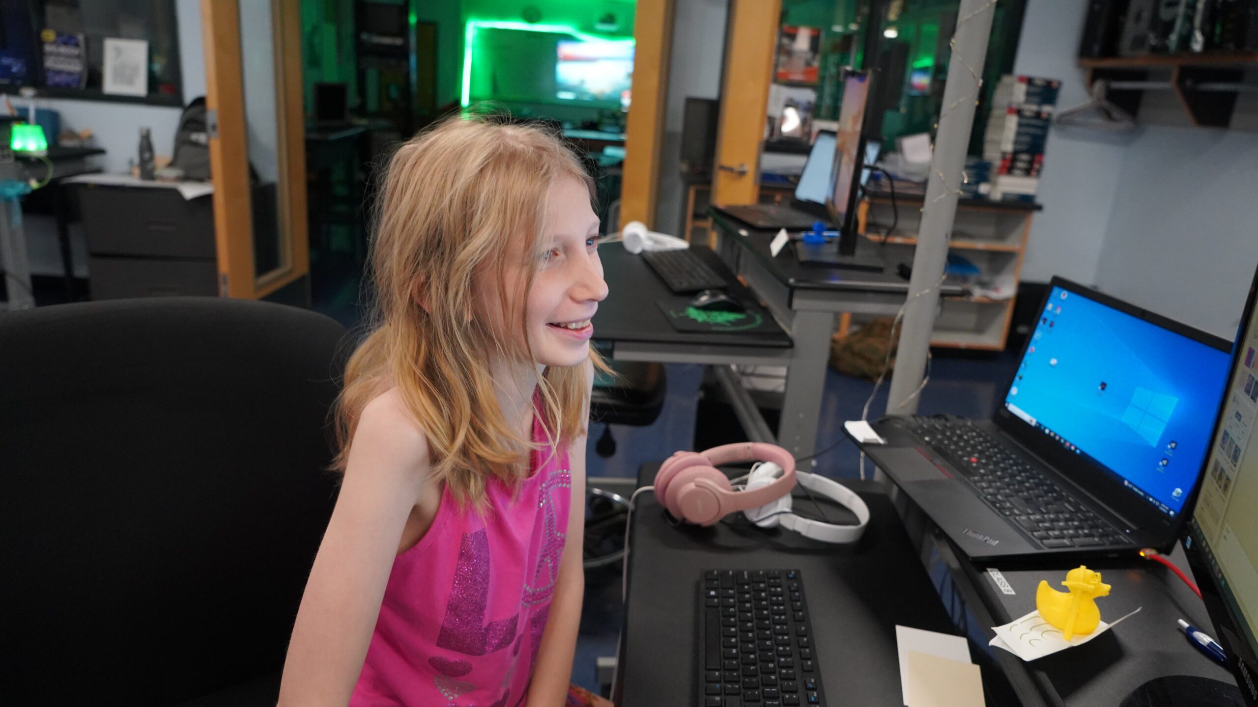 A middle school female smiling as she looks at a desktop computer